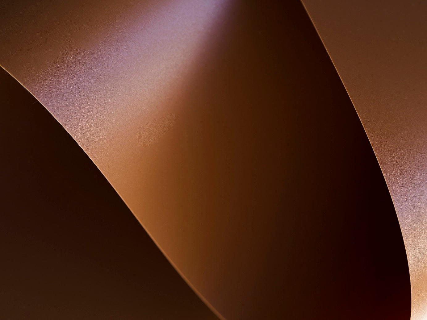 Curved copper-colored sheets on a dark background