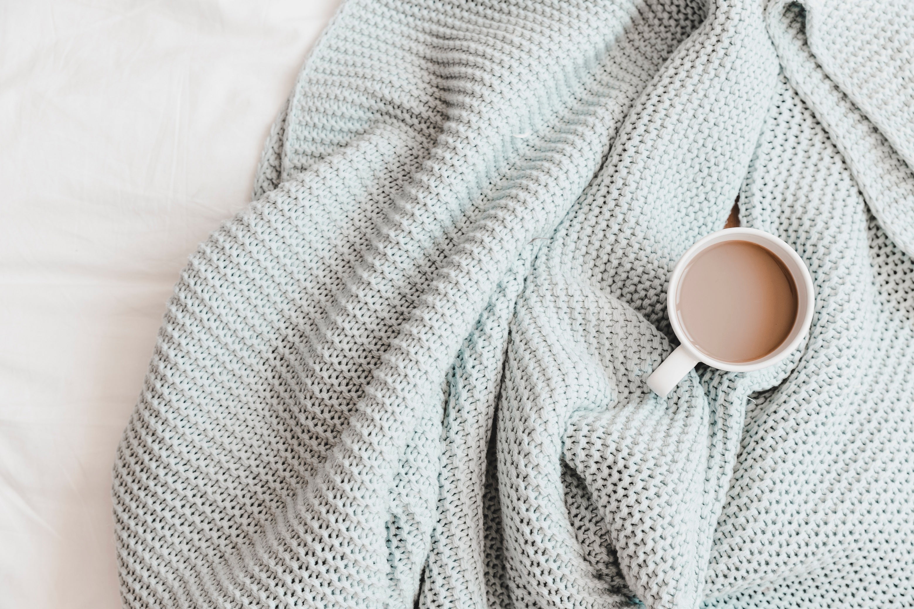 Pale knitted blanket with a mug on top