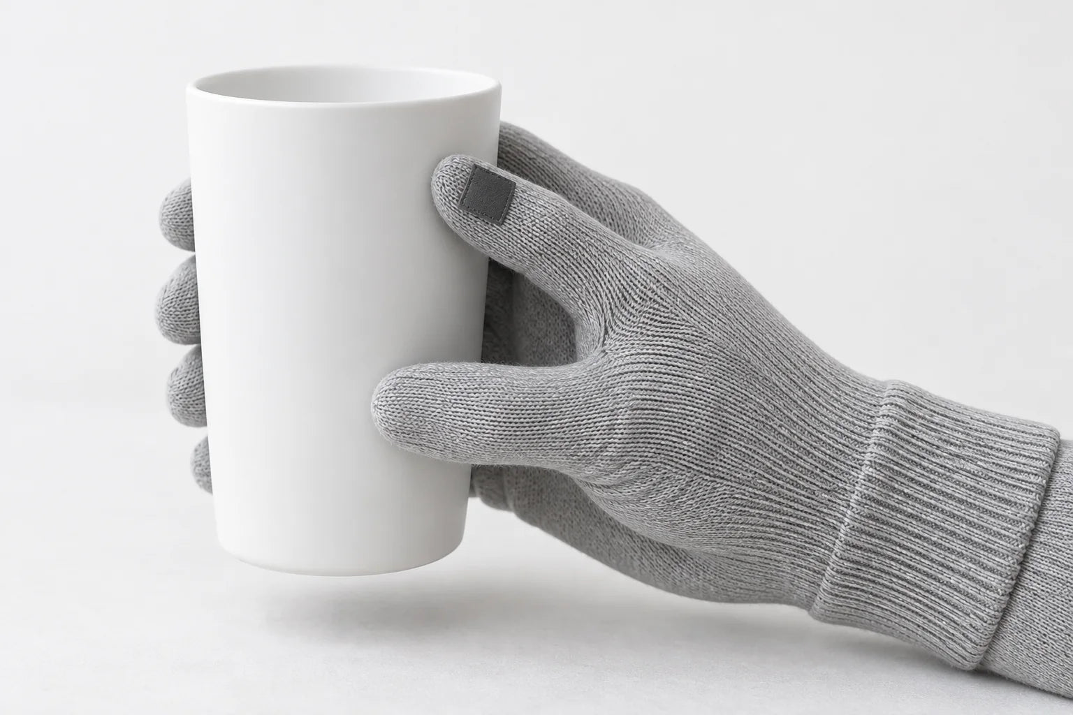 Concept illustration of a knitted glove holding a cup, with a small patch suggesting a possible sensing region near the finger.